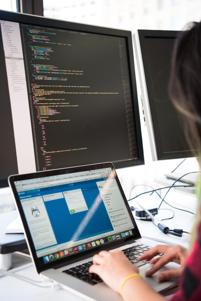 Professional IT services image showing Individual working on a laptop at a desk with two monitors displaying code in a bright, modern IT workspace. for managed IT services, cybersecurity, network infrastructure, cloud solutions, and business IT support. - BKY Technologies Professional IT services image showing Individual working on a laptop at a desk with two monitors displaying code in a bright, modern IT workspace. for managed IT services, cybersecurity, network infrastructure, cloud solutions, and business IT support.